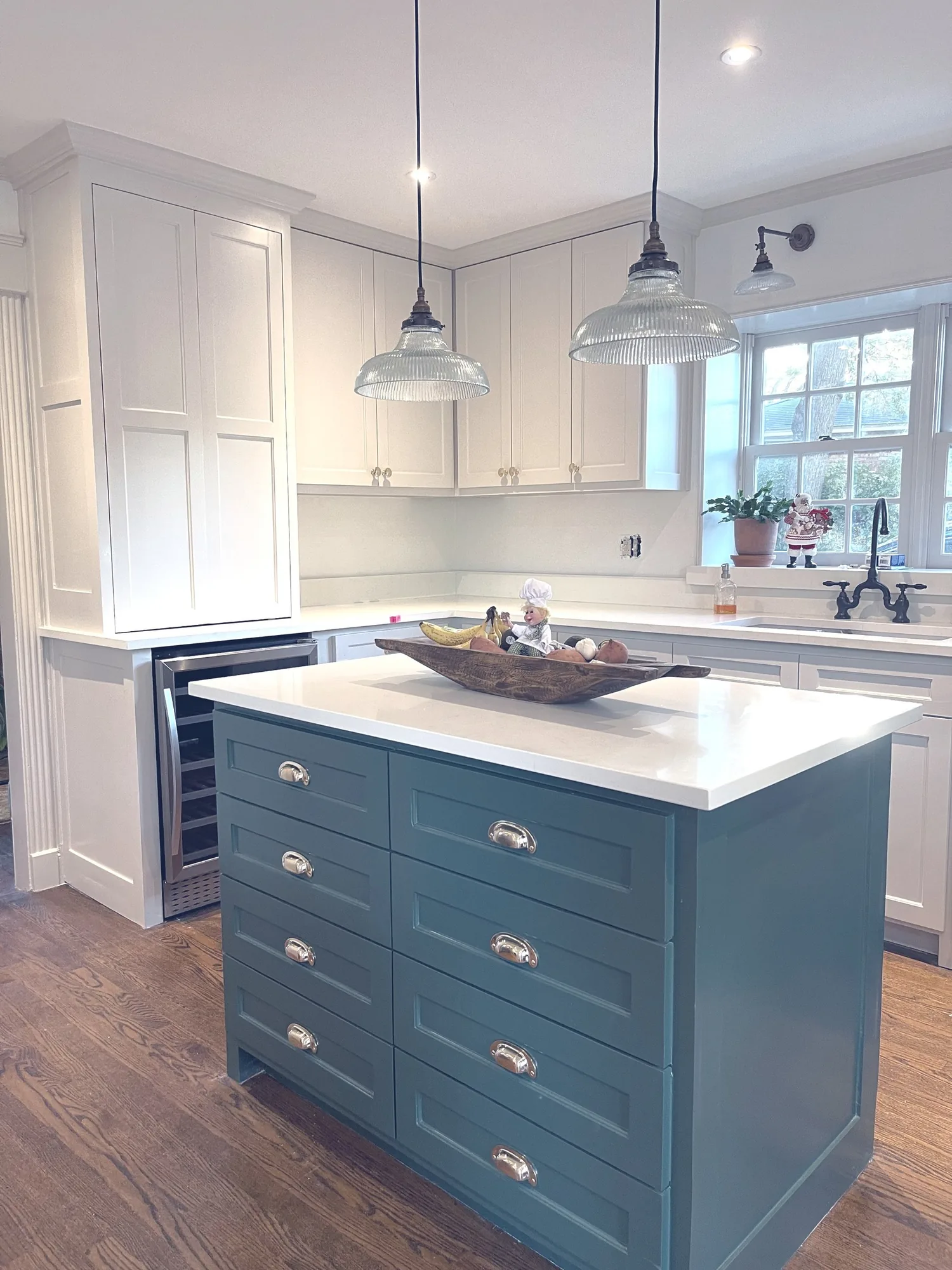 Kitchen with a blue painted island, glass pendant lights, and white perimeter cabinetry