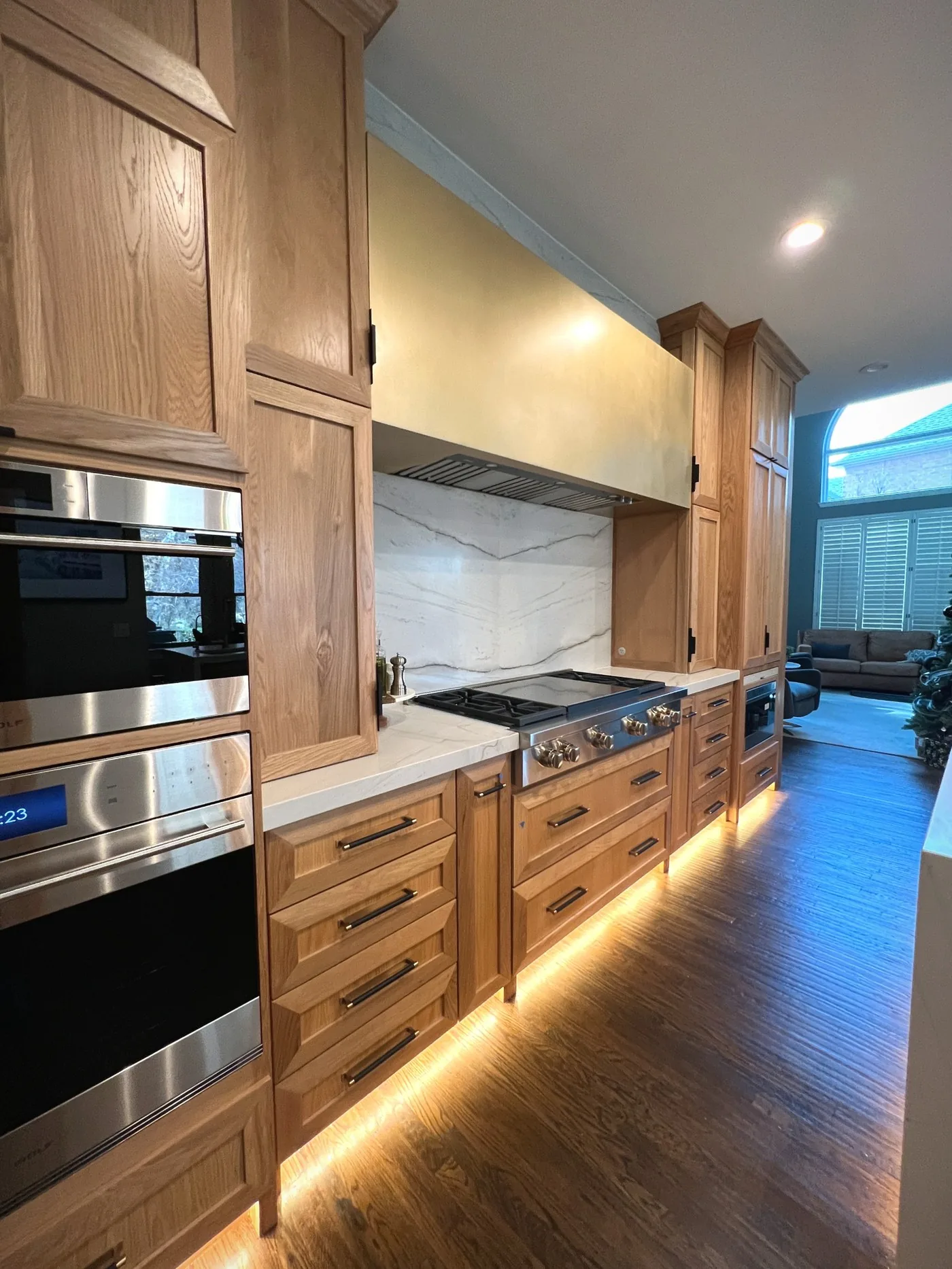 Oak kitchen run with warm lighting under the upper cabinets and along the base