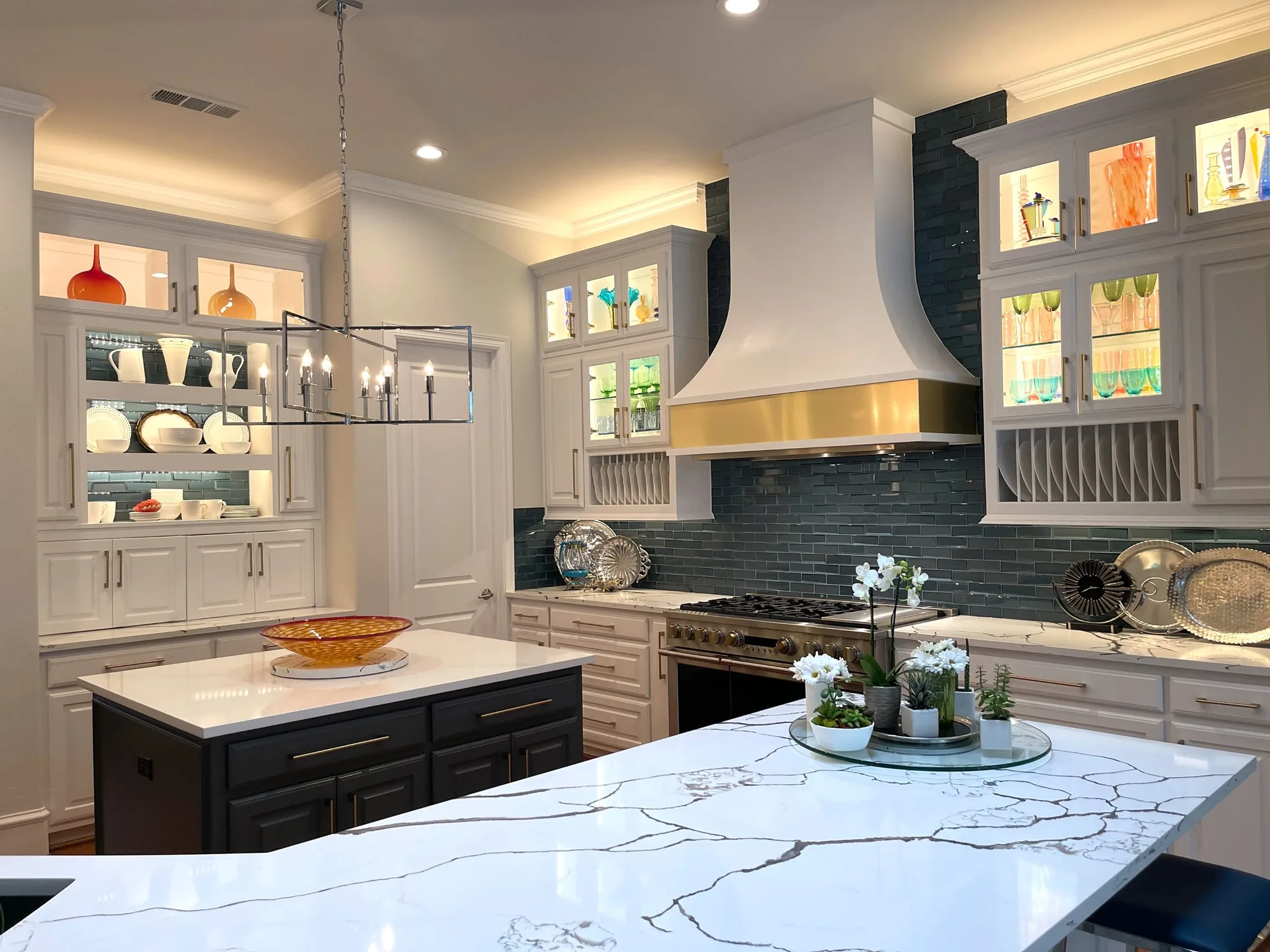 Zapata Custom Cabinets kitchen with lit glass-front upper cabinets, a white hood, and a marble island