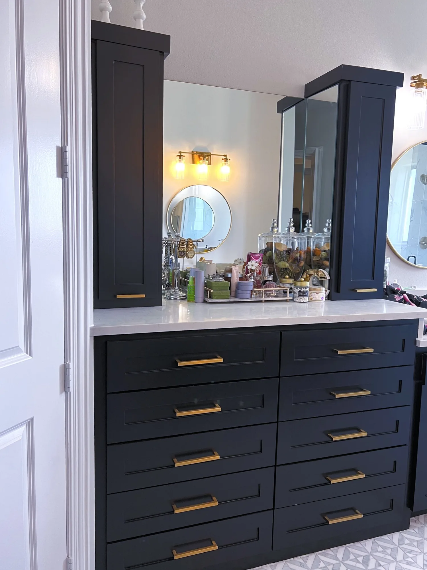 Navy bathroom vanity with brass hardware, deep drawer banks, and tall flanking cabinets